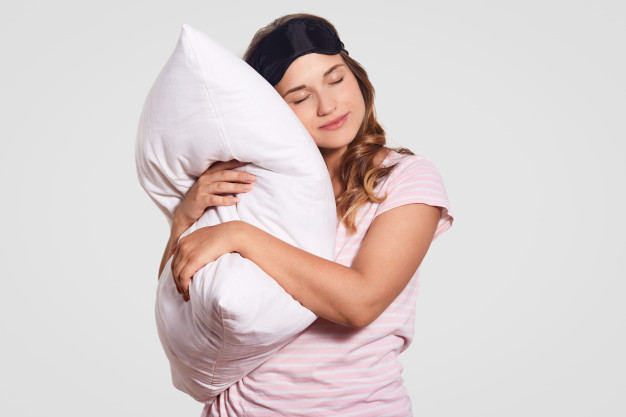 photo-european-woman-with-healthy-skin-leans-soft-pillow-wears-pyjamas-eyewear-head-poses-alone-white-has-sleepy-look-people-good-morning-concept_176532-8502
